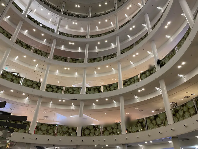 Rundes Atrium eines Kaufhauses, Glasgeländer auf allen Etagen mit bedruckter Folie