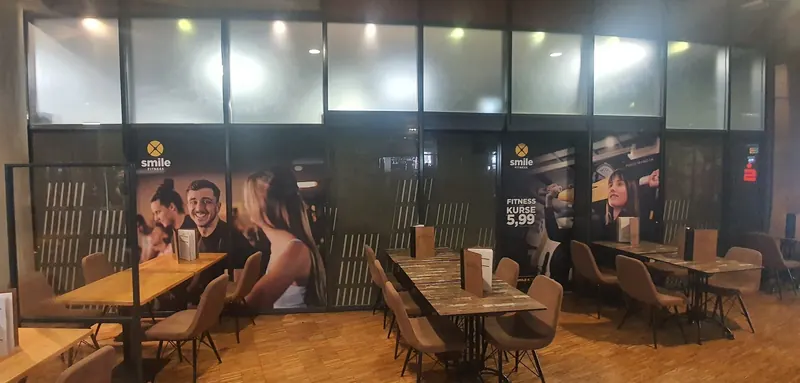 Glastrennwand in einem Gastrobereich mit großflächigem Digitaldruck, Logo und Angebotstext