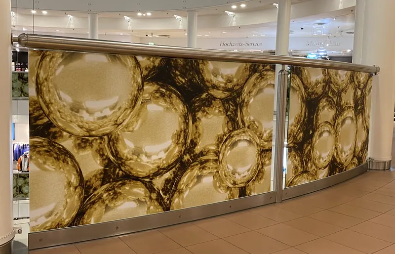 Glasgeländer im Kaufhaus mit großflächigem Digitaldruck in Gold