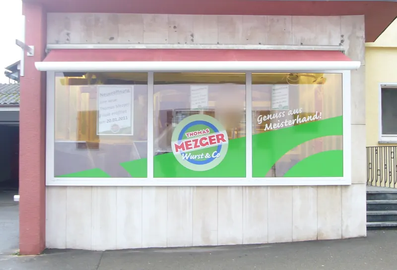 Schaufenster einer Metzgerei mit großflächigem Digitaldruck, Logo und Slogan