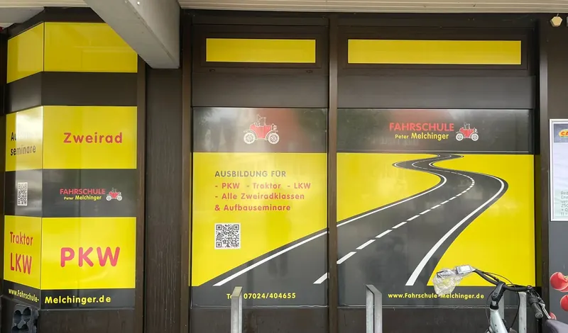 Schaufenster einer Fahrschule mit gelber Lochfolie: von außen vollflächige Werbung, von innen Durchsicht