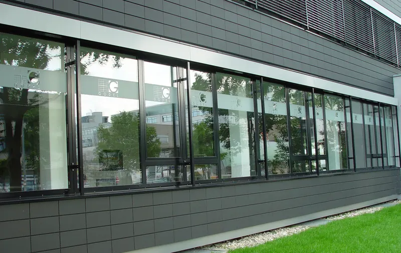 Fensterband eines Bürogebäudes mit mattiertem Sichtschutzstreifen und wiederholtem Firmenlogo