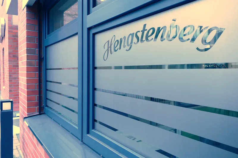 Fensterfront eines Firmengebäudes mit Sichtschutzfolie in Streifen und großem Logo-Schriftzug