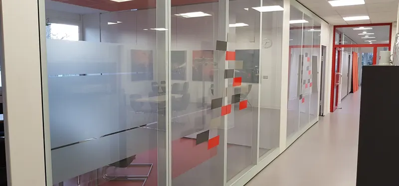 Büroflur mit mehreren Glaswänden, durchgehend mit Streifen- und Quadratmuster foliert