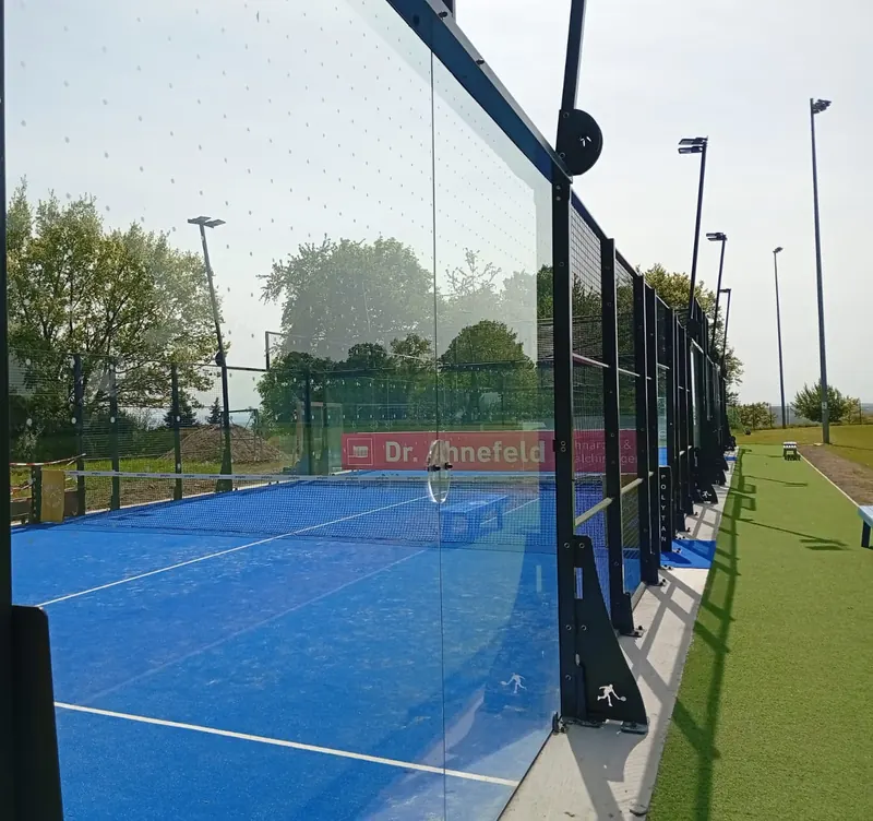 Glaswand eines Outdoor-Padelplatzes mit Vogelschutzmarkierung aus kleinen Punkten