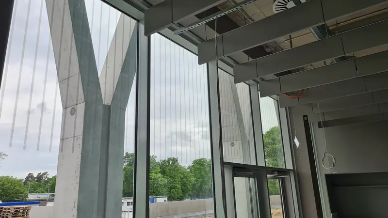 Hohe Glasfassade im Foyer eines Stadions mit vertikalen Vogelschutz-Linien
